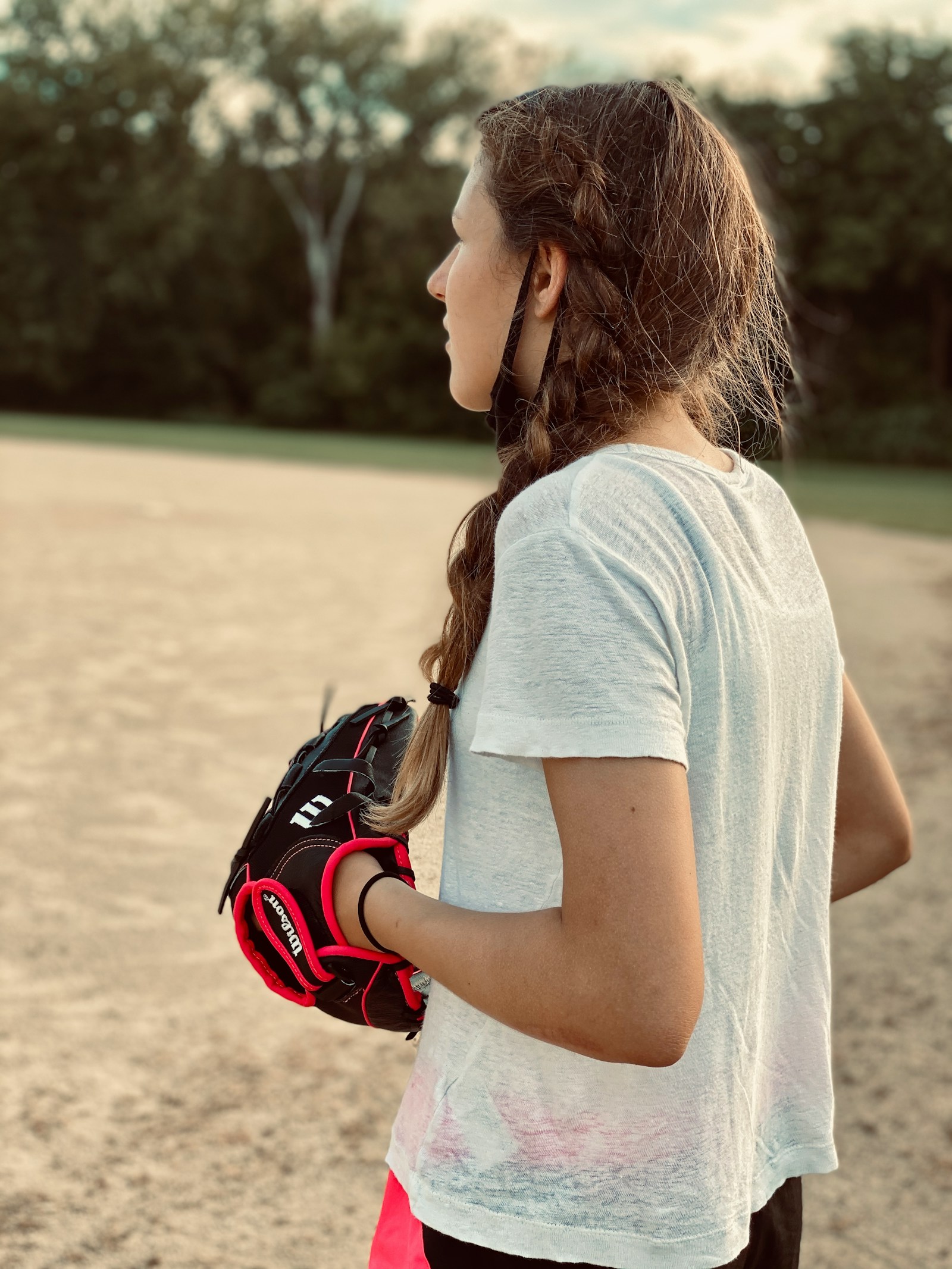 Softball player holding a glove near the dugout